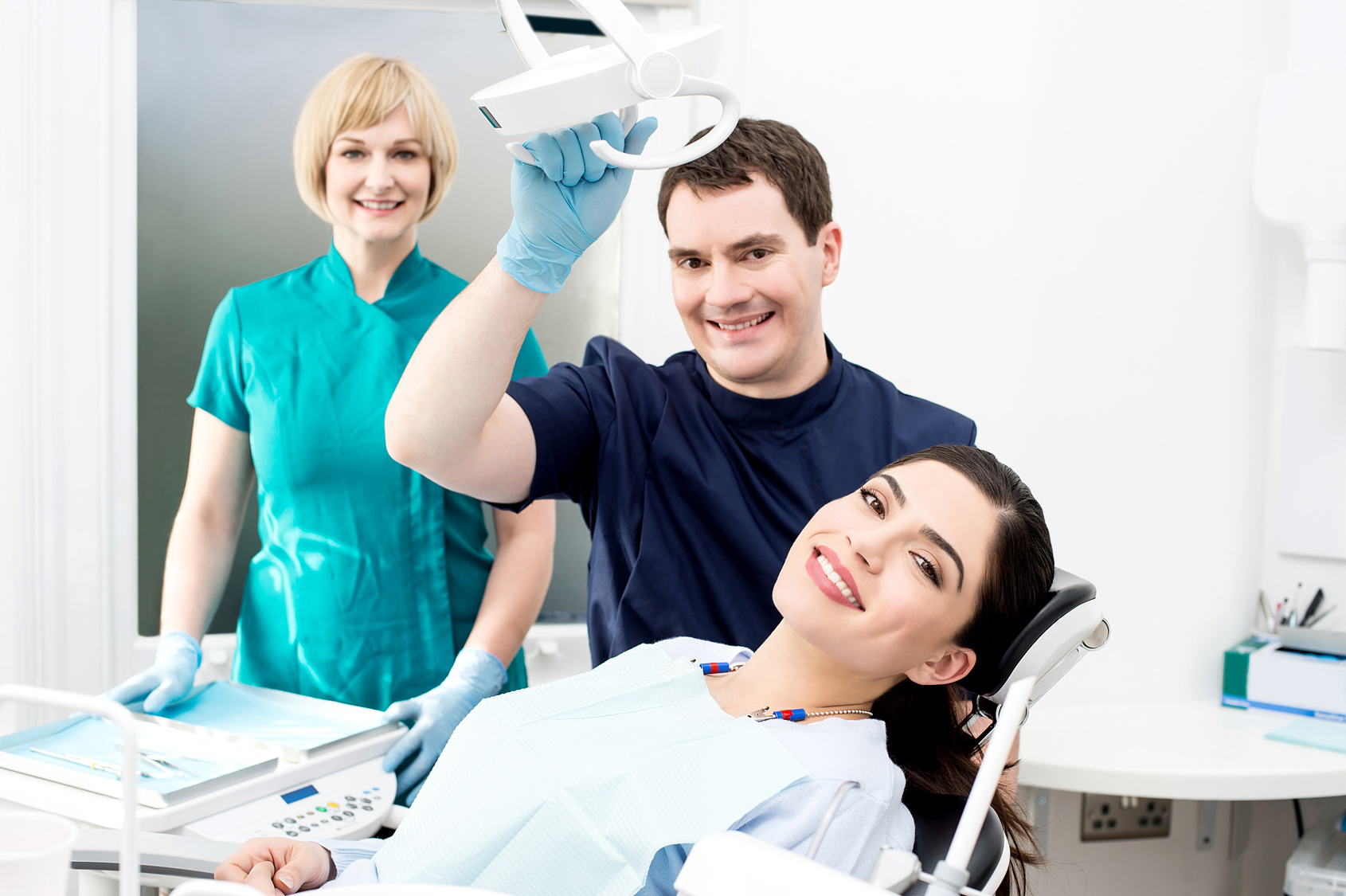Smiling dentist and assistant with female patient
